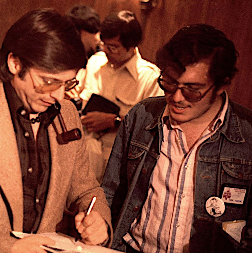 Harlan Ellison signs an autograph for a fan. Ellison is left handed and smoked a pipe.
