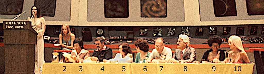 A long table is set up on the bridge set, featuring two hosts and a panel of costume-contest judges. 