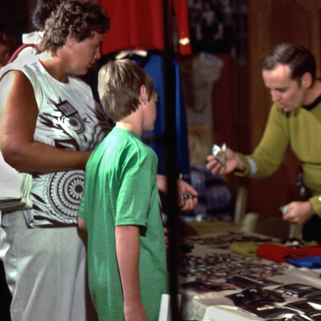 The main dealers' room. A boy and his mother look over a table of collectibles.