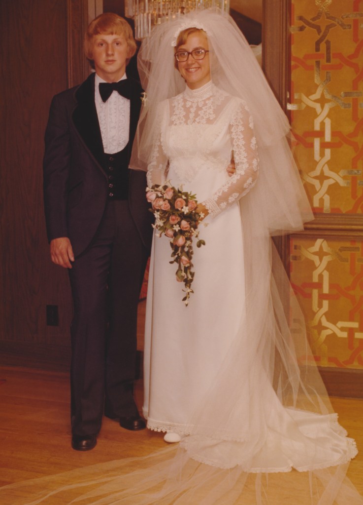 A wedding photo, showing a happy young copy in a 1970s tuxedo and wedding dress.  