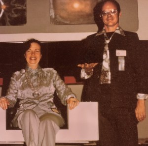 A two shot of Bjo and John Trimble, with her sitting in the captain's chair and John standing beside. 