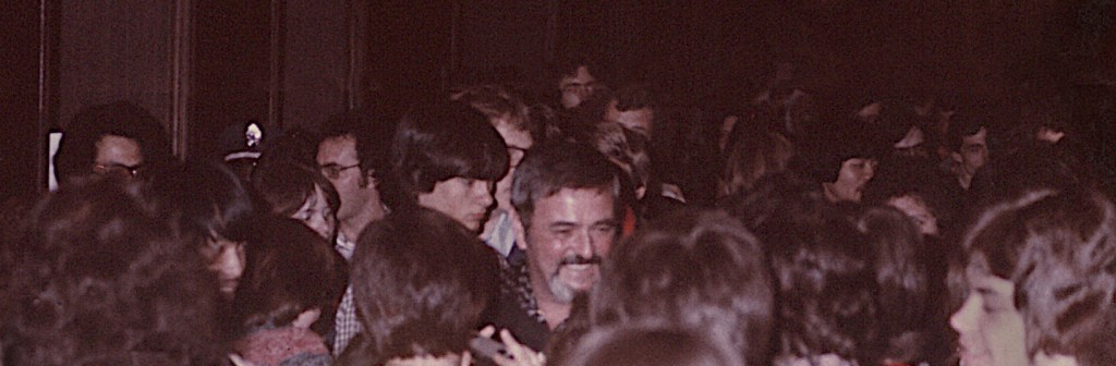 Star Trek actor James Doohan is seen surrounded by a large group of fans. Doohan seems relaxed and happy. 
