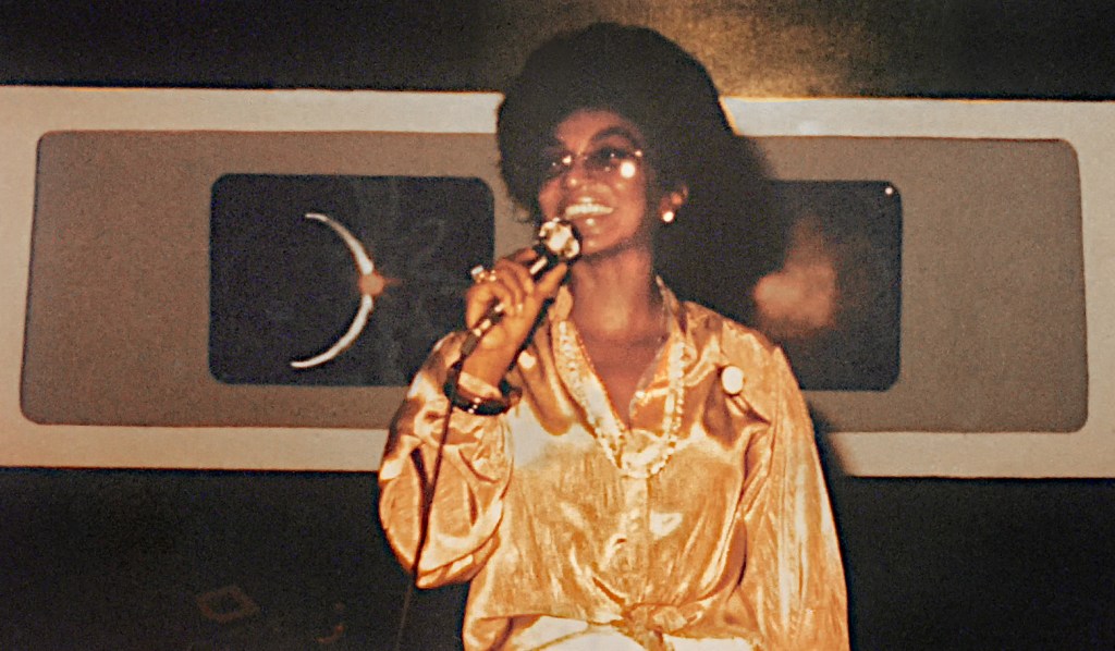 Star Trek actor Nichelle Nichols on stage. She is wearing a gold-coloured top and a gold necklace. 